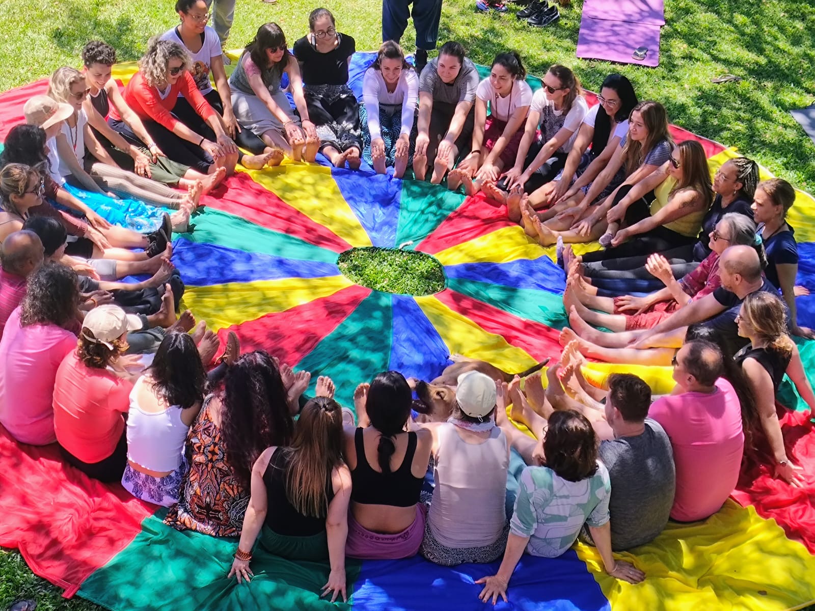 Grupo sentado em círculo sobre tapete colorido em atividade cooperativa
